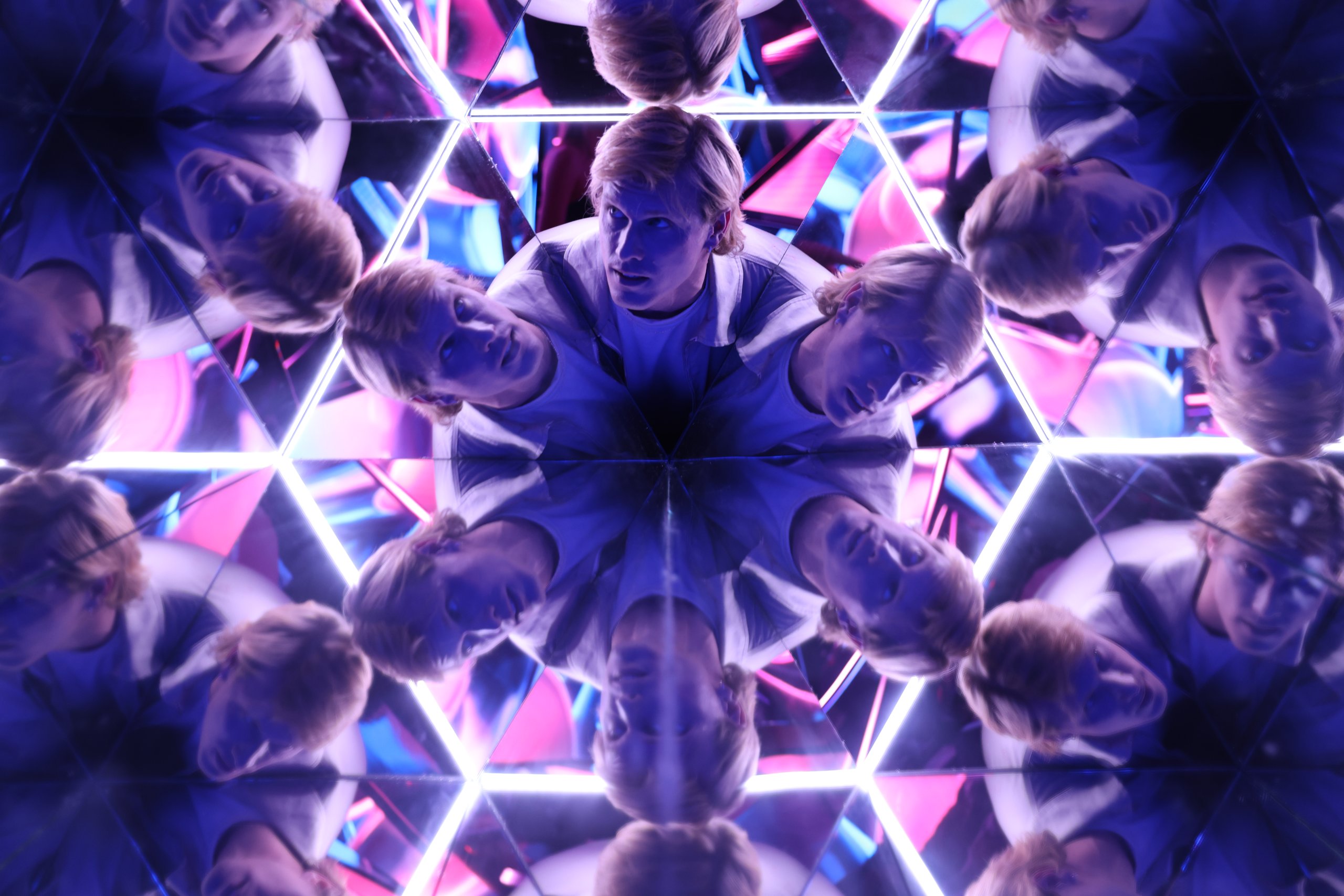Person surrounded by colorful neon lights and mirrors in the Kaleidoscope room, an immersive installations at Edge NYC, 30 Hudson Yards